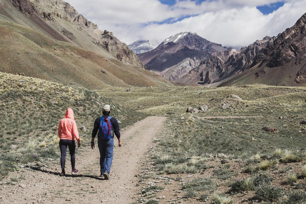 couple-walking-dirt-track-near-mountain-range